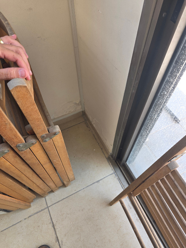 פינת מרפסת בדירה יד שנייה שהוסתרה על ידי כיסאות מתקפלים